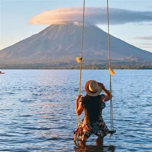 Вид сзади на молодую девушку, сидящую на качелях с видом на вулкан Консенпсьон на острове Ометепе, Никарагуа