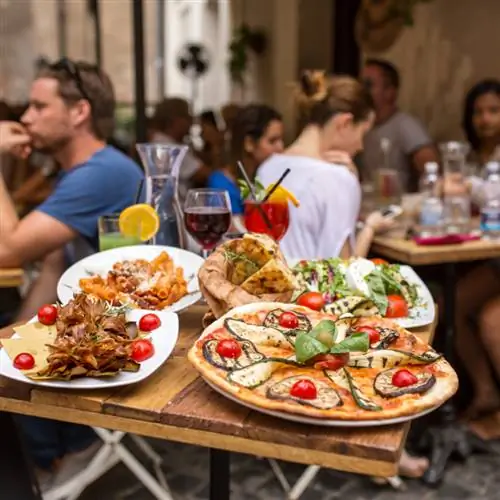 на столе в Риме выставлены продукты, выставленные на продажу в ресторане, включая пиццу и пасту.