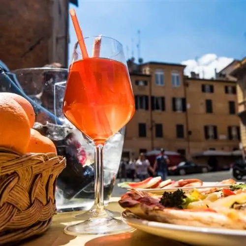 стакан апельсинового аперола стоит на столе с едой в Риме