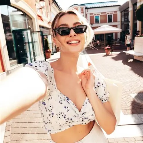 Молодая женщина в солнцезащитных очках и летнем платье делает селфи в Италии, Южная Европа