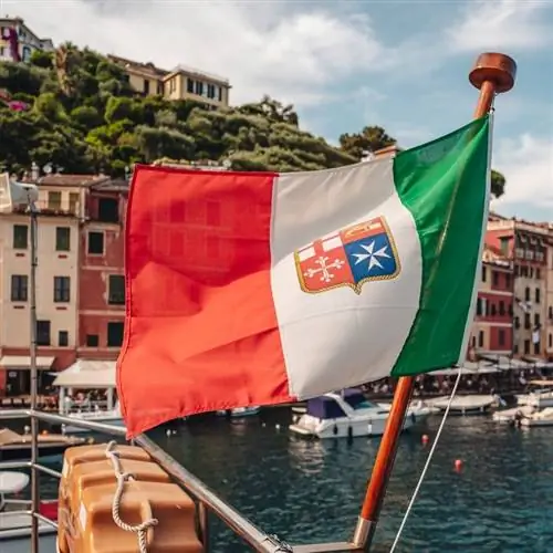Итальянский флаг развевается с портом Портофино, размытым на заднем плане, Лигурийское море, Италия