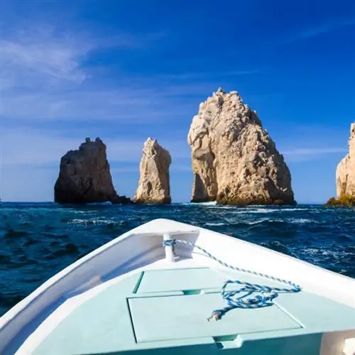 Нос лодки приближается к большому скальному образованию в океане в Кабо-Сан-Лукас, Мексика.