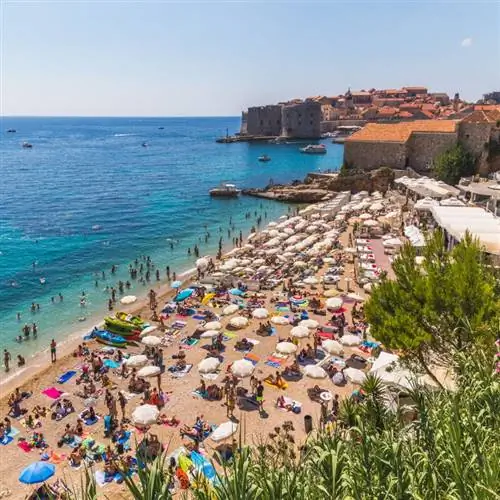 Пляж Банье, Адриатическое море и Старый город Дубровника летом. Можно увидеть большое количество людей.