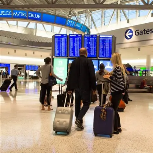 Вид на терминал 4 JetBlue в международном аэропорту Джона Ф. Кеннеди, также известном как JFK, с путешественниками и табло вылета.