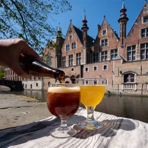 Бельгийское пиво на столе с видом на канал в Брюгге, Бельгия