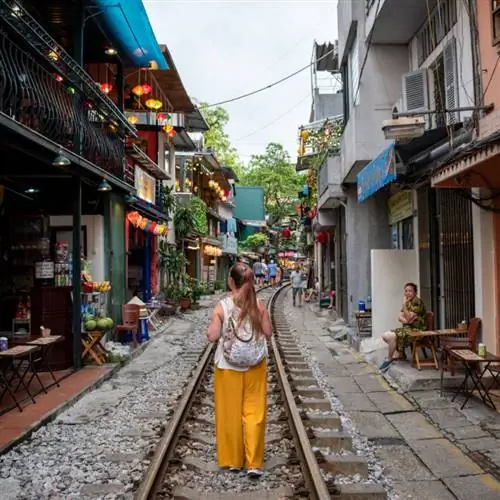 Одинокая путешественница в желтых штанах идет по железнодорожной улице в Ханое, Вьетнам.