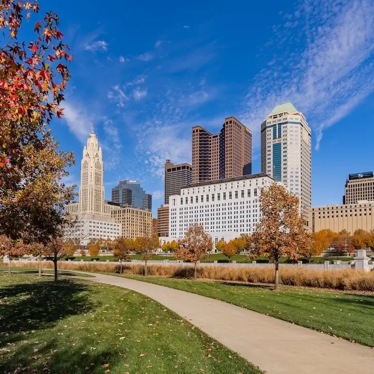 Тротуар у реки Скиото осенью на фоне центра Колумбуса, штат Огайо.