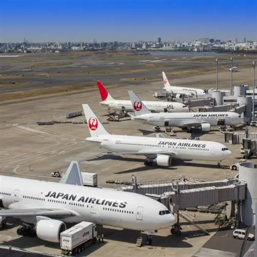 Белые и красные пассажирские самолеты Boeing 777 Dreamliner Japan Airlines (JAL) готовятся к взлету в здании терминала международного аэропорта Токио.