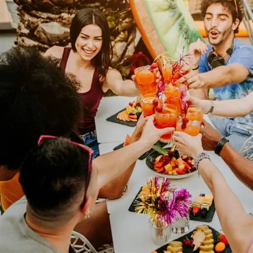 разнообразные друзья празднуют хорошей едой и напитками