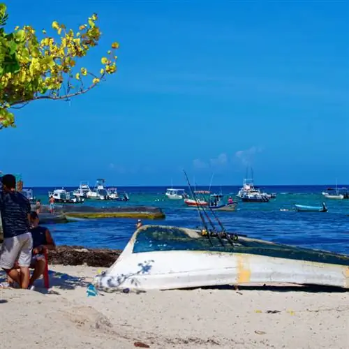 Перевернутая лодка на переднем плане и лодки в океане позади. Пляж в Плайя-дель-Кармен, Мексика.