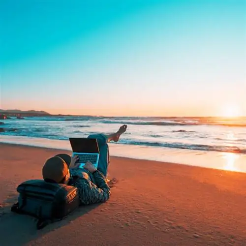 цифровой кочевник на пляже с ноутбуком на закате