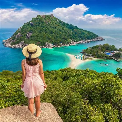Молодая женщина, стоящая на вершине скалы с видом на пляж и природный объект в Таиланде, Юго-Восточная Азия