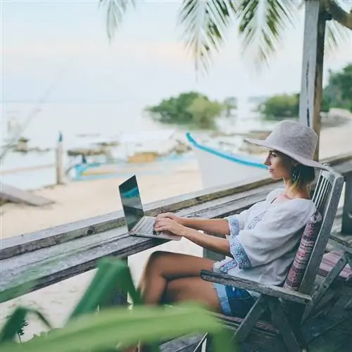 Цифровой кочевник, работающий с компьютером на пляже