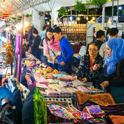 Люди покупают одежду и красочные коврики на уличном рынке в Чиангмае, Таиланд, Юго-Восточная Азия