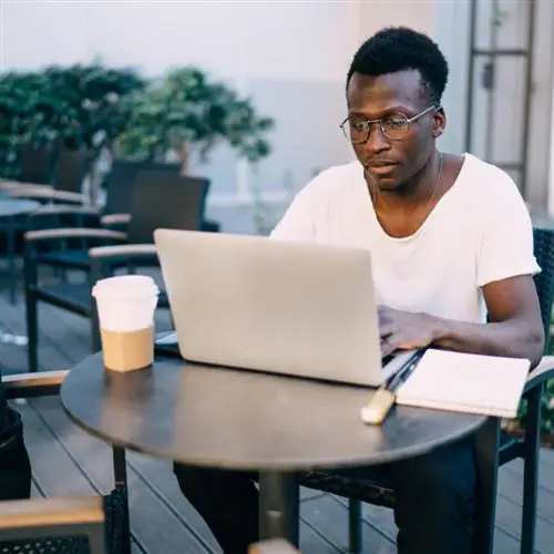 Мужчина с кофе работает за компьютером как цифровой кочевник