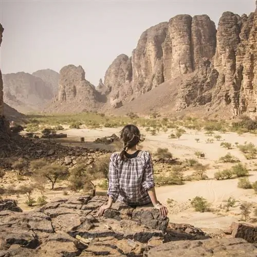 Женщина-туристка сидела на камне, любуясь суровым ландшафтом Джанет в Южном Алжире, Северная Африка