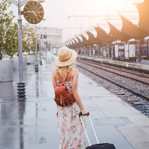 путешествие на поезде, женщина с багажом ждет на платформе железнодорожного вокзала