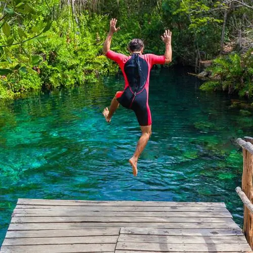 Молодой турист-мужчина прыгает в сенот на Ривьере Майя, Кинтана-Роо, Мексика