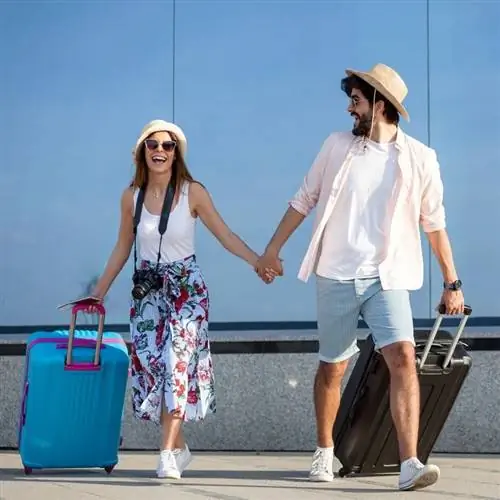 Счастливая молодая пара в летней одежде покидает аэропорт после международного путешествия