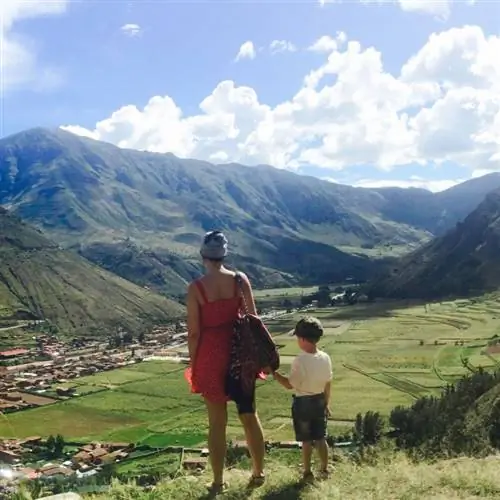 мать и сын держатся за руки и смотрят на горы