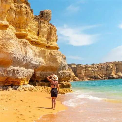 Женщина гуляет по пляжу Прайя-да-Коэлья, Алгарве, Португалия