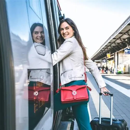 Улыбающаяся женщина забирается в поезд на неизвестном вокзале