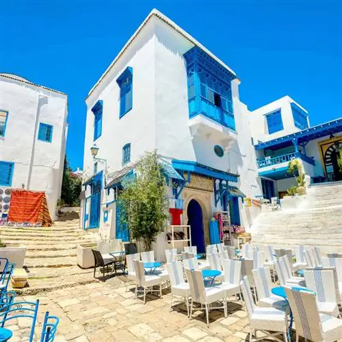 Традиционные побеленные дома и рестораны под открытым небом с голубыми ставнями в старом Сиди-Бу-Саиде, в Тунисе, на средиземноморском побережье Северной Африки