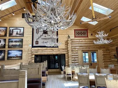 В обеденном зале лоджа Silvies Valley Ranch есть ресторанные кабинки и столы. Большие люстры из лосиного сарая свисают с потолка с деревянными балками в Сенеке, штат Орегон. В обеденном зале лоджа Silvies Valley Ranch есть ресторанные кабинки и столы. Большие люстры из лосиного сарая свисают с потолка с деревянными балками в Сенеке, штат Орегон.