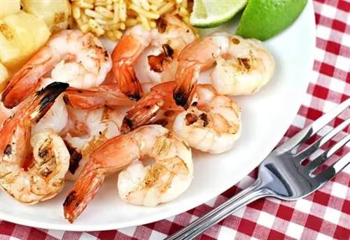 Свежие креветки на гриле на тарелке с жареным ананасом, рисом и лаймом.