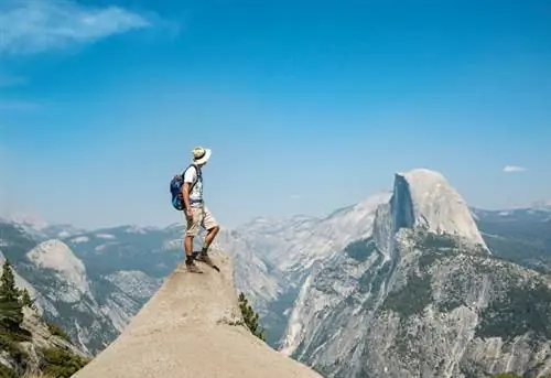 Молодой человек стоит на выступе и смотрит на Хаф-Доум, вид с Глейшер-Пойнт, Йосемитский национальный парк, Калифорния, США