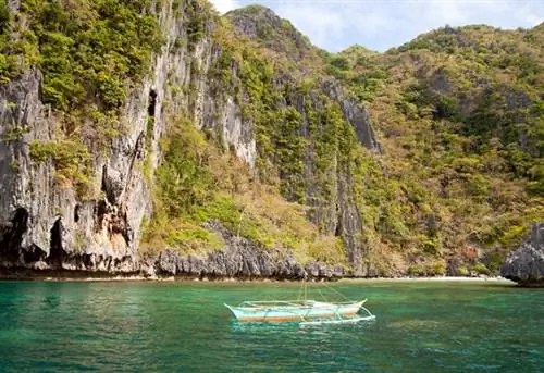 Лодка с аутригером у крутого известнякового побережья острова Тапиутан, архипелаг Бакуит, Эль-Нидо, Палаван, Филиппины, Азия
