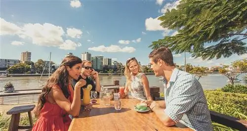 Люди едят еду за столом для пикника на берегу реки