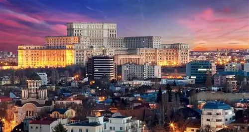 Массивное многоуровневое здание возвышается над плоским городом под ним.