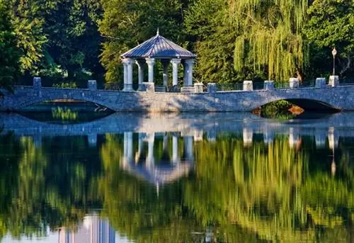 Мост и беседка, отражающиеся в парковой реке