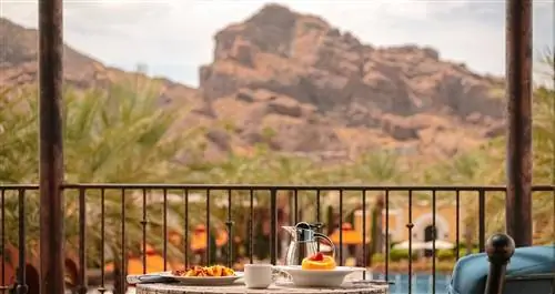 Завтрак на столе с видом на бассейн. На заднем плане видны песчаные горы