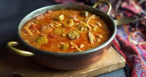 Чаша красного супа с плавающими внутри кусочками бамии.