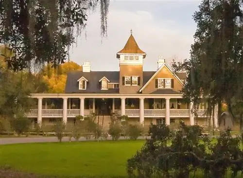 Солнечный свет светит на черно-белый дом с длинным крыльцом