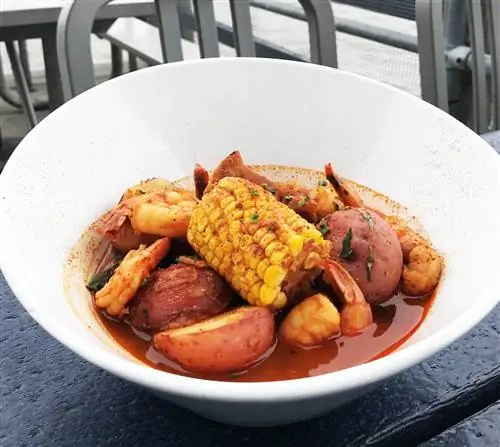 Креветки, колбаса, кукуруза и картофель в белой миске
