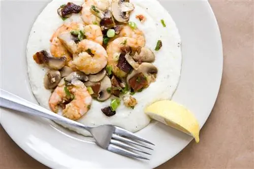 Креветки и грибы на белой крупе в тарелке