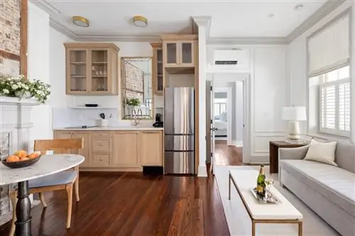 Современный серый диван и светло-коричневая мебель в комнате с белыми стенами