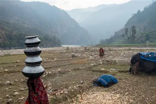 Женщина-Рауте несет на голове стопку мисок.