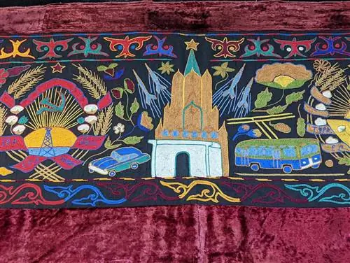 Кыргызский шырдак с изображением городской сцены с автомобилем, автобусом, зданием и ракетами.