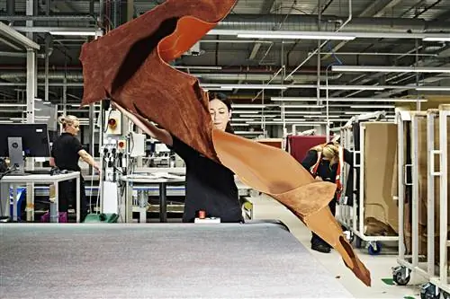 Рабочий готовится вырезать кусок кожи для интерьера.