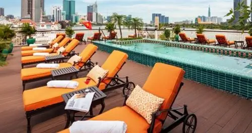 верхняя палуба речного круизного судна Uniworld Mekong Jewel с оранжевыми шезлонгами, бассейном и городским фоном