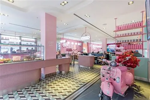 Ресторан EL&N в аэропорту Хитроу с розовой Vespa на переднем плане и розовым буфетом и банкетками на заднем плане.