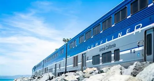 Общий план лайнера Amtrak California Surfliner, летящего по следам на скале у океана в Марипозе, Калифорния.