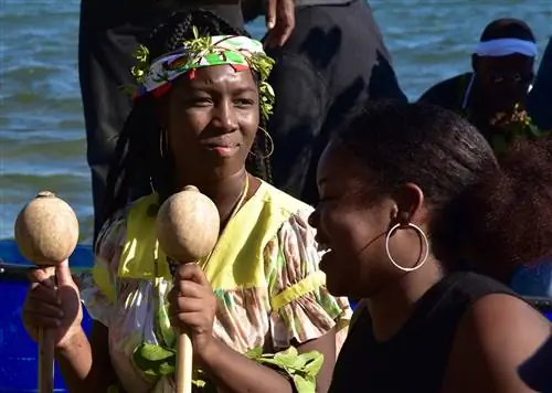 Женщины и мужчины прибывают на лодках во время воссоздания поселения народа гарифуна в Белизе.