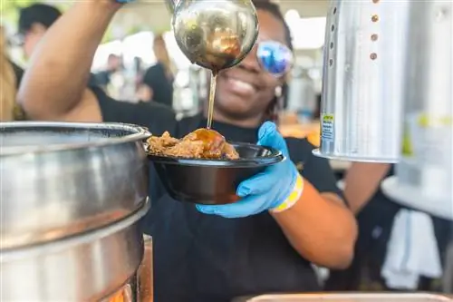 Продавец подает жареную курицу на фестивале Французского квартала.