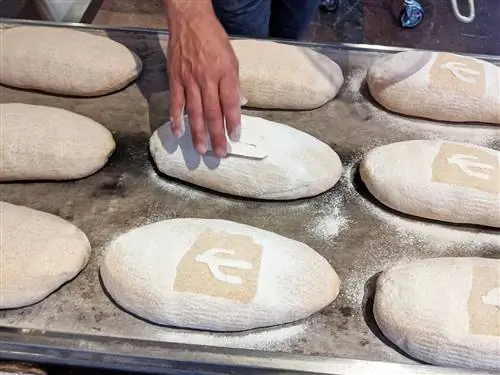 Дон Герра просеивает муку на трафарет кактуса сагуаро для буханок Heritage в Barrio Bread.