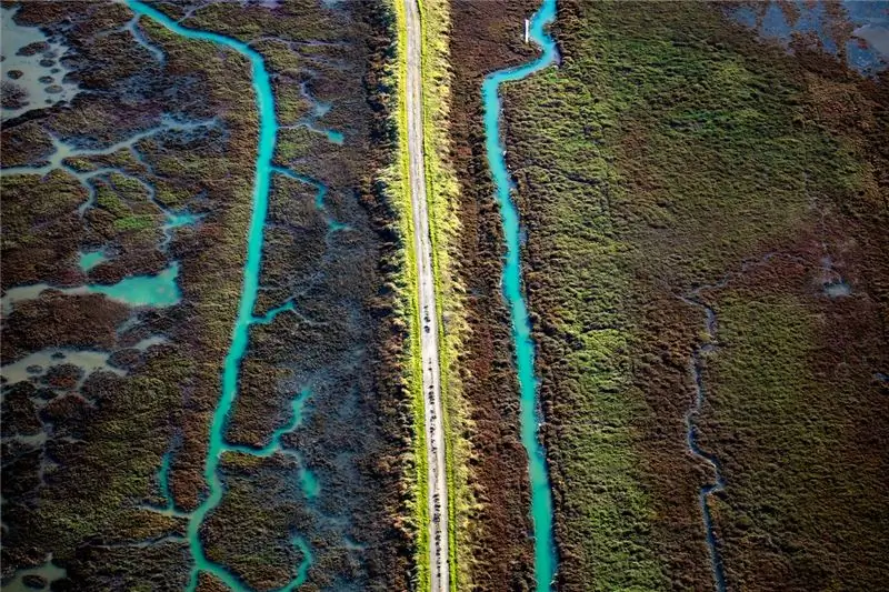 Два ручья текут параллельно дамбе через восстановленные водно-болотные угодья Южного залива